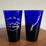 Love is on Lake George text over/under our Lake/Mountain scene; back side has the silhouette of Lake George printed in white on a blue glass.